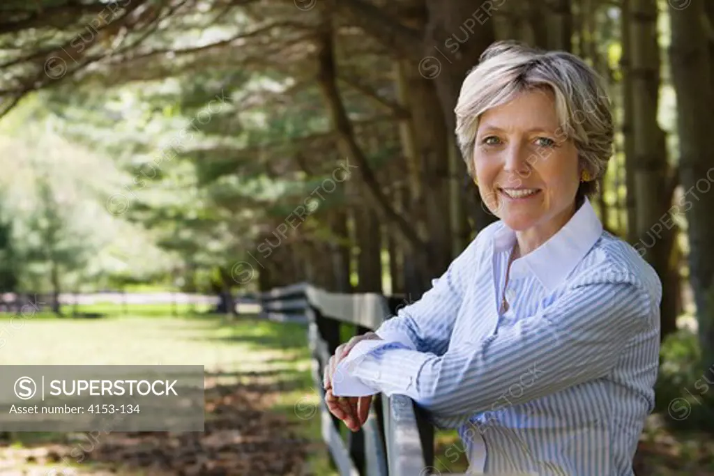 USA, Mature woman leaning on rail fence