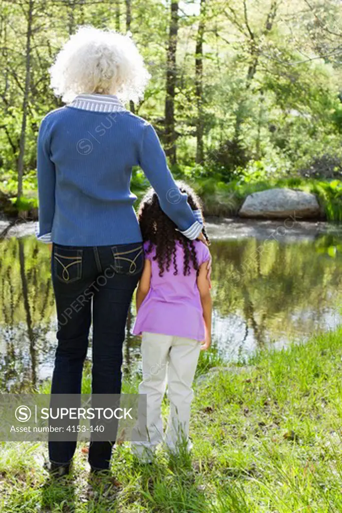 USA, Grandmother and granddaughter standing near pond