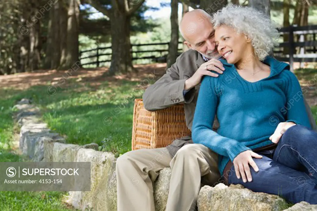 USA, Mature couple sitting in park, man massaging woman