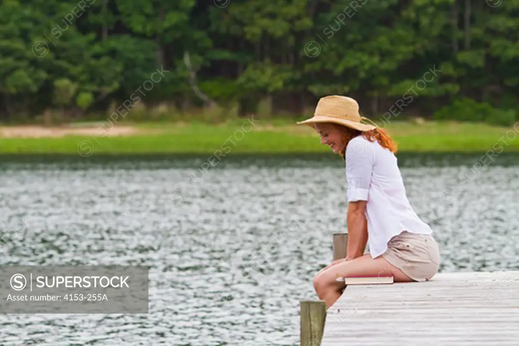 Young woman wearing straw hat sitting on jetty