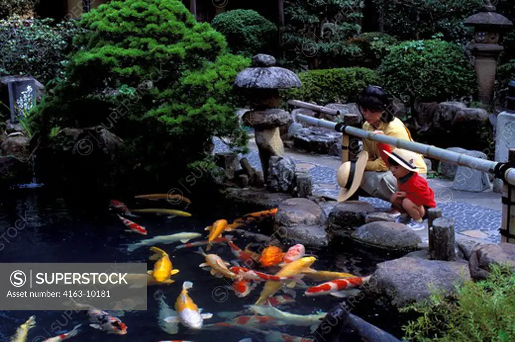 JAPAN, HONSHU IS.,MATSUE, RESTAURANT WITH JAPANESE GARDEN, MOTHER WITH BOY WATCHING CARP