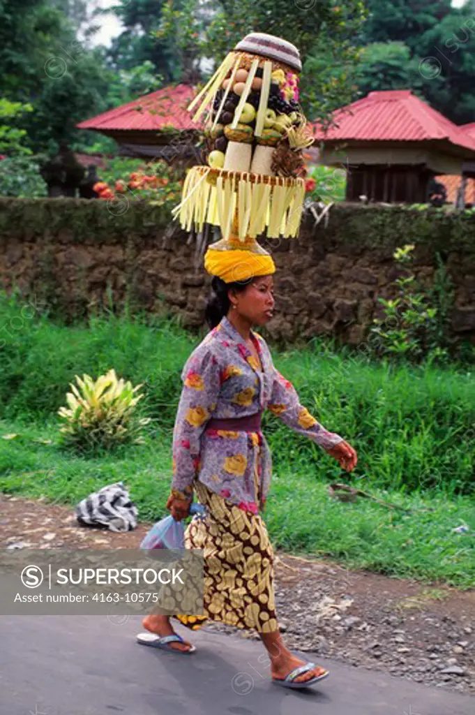INDONESIA, BALI, WOMAN WITH OFFERING ON THE WAY TO TEMPLE