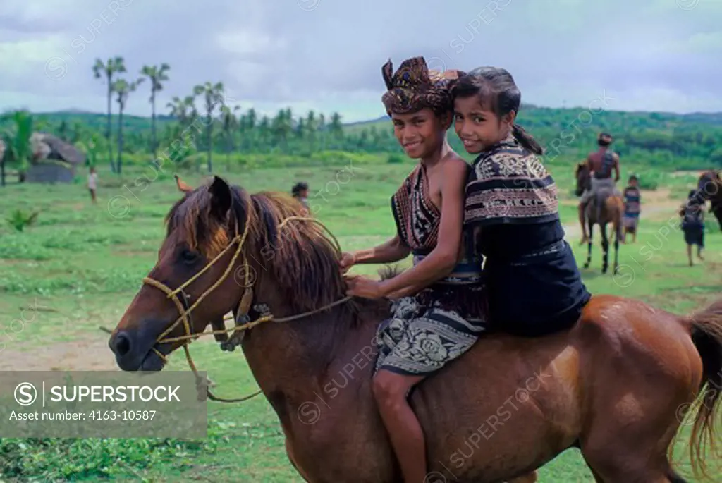 INDONESIA, SAWU (SEBA) ISLAND, TEENAGE BOY & GIRL ON HORSE IN TRADITIONAL IKAT COSTUMES