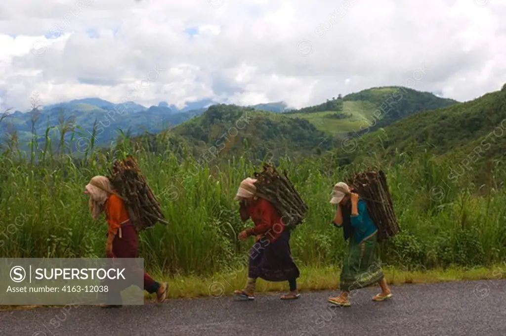 LAOS,  NEAR PHOU KHOUN, WOMEN WITH FIREWOOD WALKING ON STREET IN COUNTRY SITE