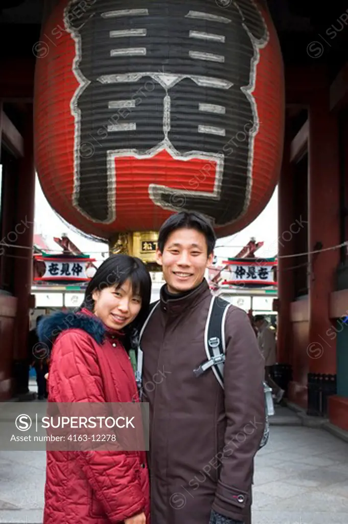 JAPAN, TOKYO, ASAKUSA SENSOJI BUDDHIST TEMPLE, YOUNG JAPANESE COUPLE POSING IN FRONT OF GATE