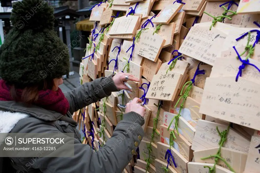 JAPAN, TOKYO, YUSHIMA TENMANGNU SHINTO SHRINE, STUDENT WRITING EMA (WOODEN PRAYER TABLET) TO HAVE GOOD LUCK WITH THEIR ENTRY EXAM
