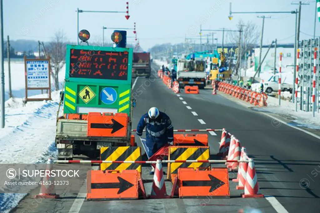 JAPAN, HOKKAIDO ISLAND, NEAR ABASHIRI, ROAD CONSTRUCTION, FLAGMAN BOWING TO TRAFFIC