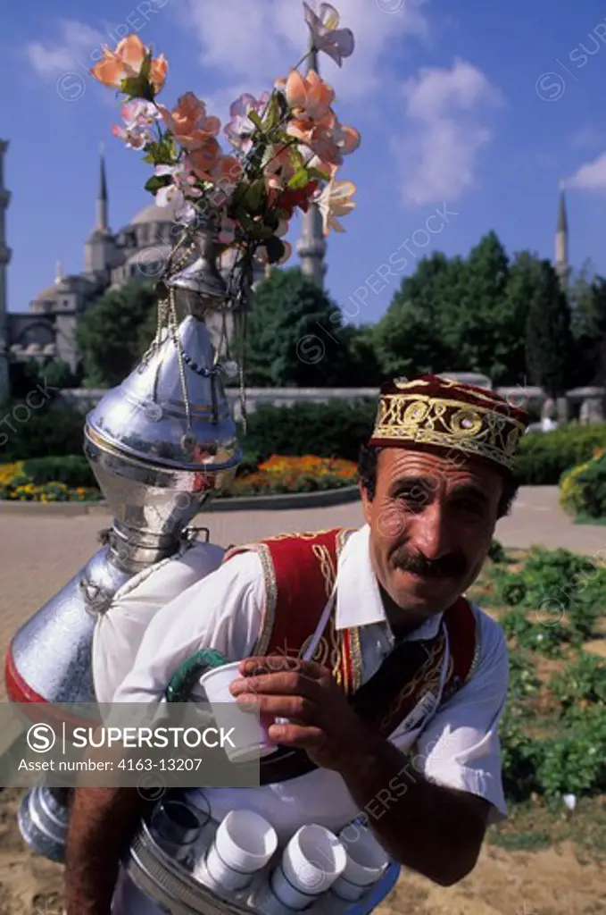 TURKEY, ISTANBUL, WATER BEARER, CLOSE-UP, BLUE MOSQUE IN BACKGROUND