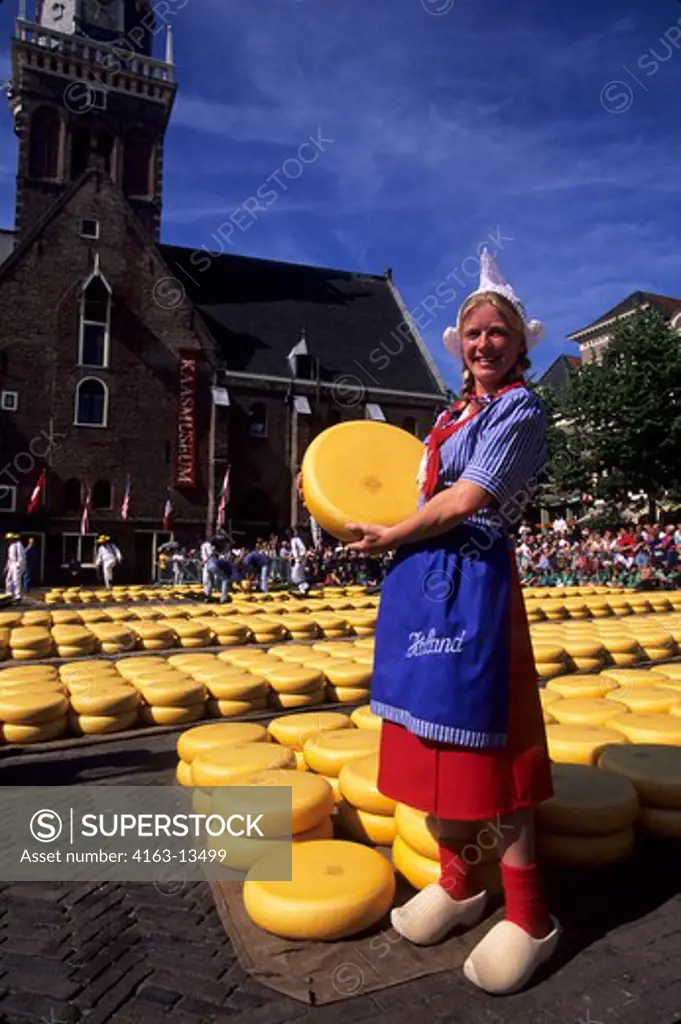 NETHERLANDS, ALKMAAR, CHEESE MARKET, GIRL IN TRADITIONAL COSTUME HOLDING GOUDA CHEESE
