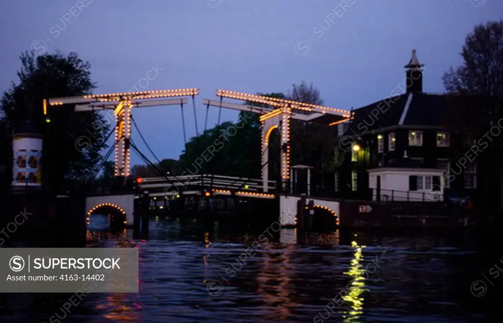 NETHERLANDS, HOLLAND, AMSTERDAM, DRAWBRIDGE ILLUMINATED AT NIGHT