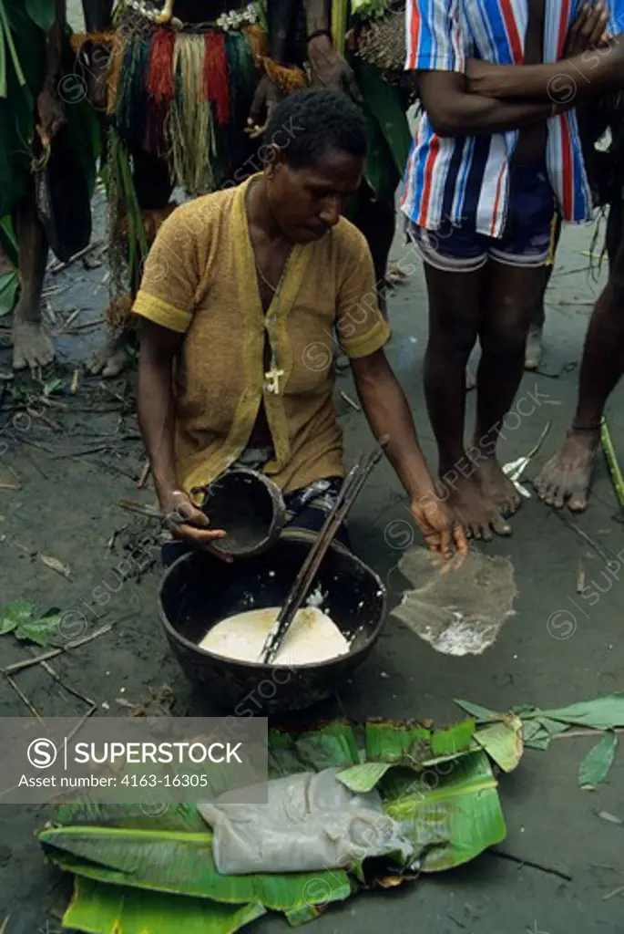NEW GUINEA, SEPIK RIVER, PRIMITIVE WOMAN PREPARING SAGO TO EAT, ON BANANA LEAVES