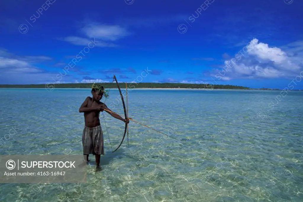 VANUATU, ANIWA ISLAND, TEENAGE BOY FISHING WITH BOW AND ARROW IN LAGOON