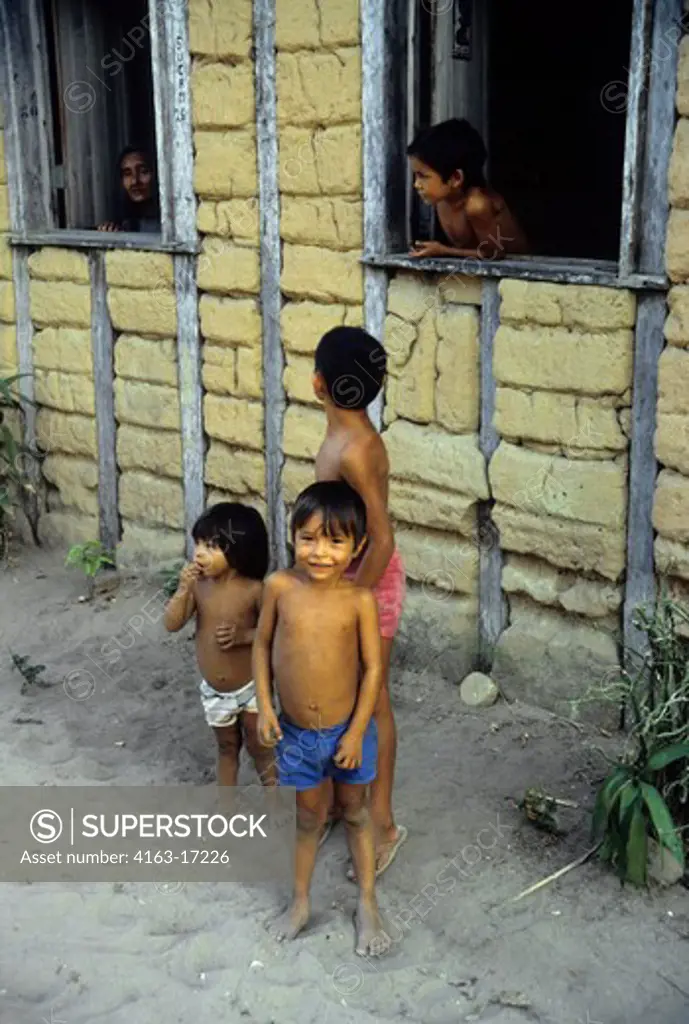 BRAZIL, AMAZON RIVER, CHILDREN IN FRONT OF MUD BRICK HOUSE