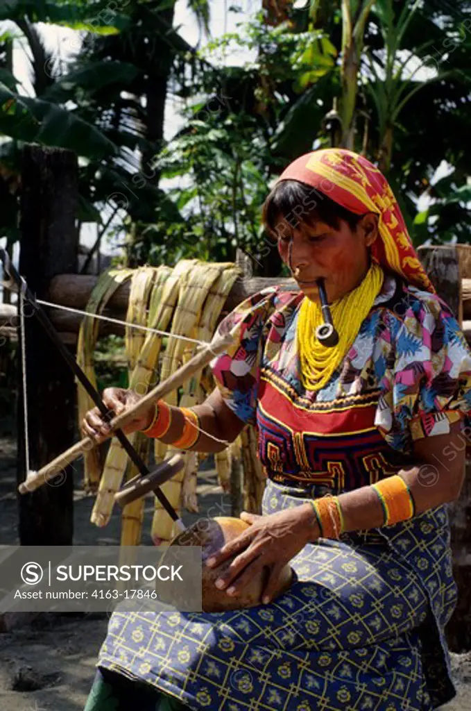 PANAMA, SAN BLAS ISLANDS, ACUATUPU ISLAND, KUNA INDIAN WOMAN USING PRIMITIVE DRILL