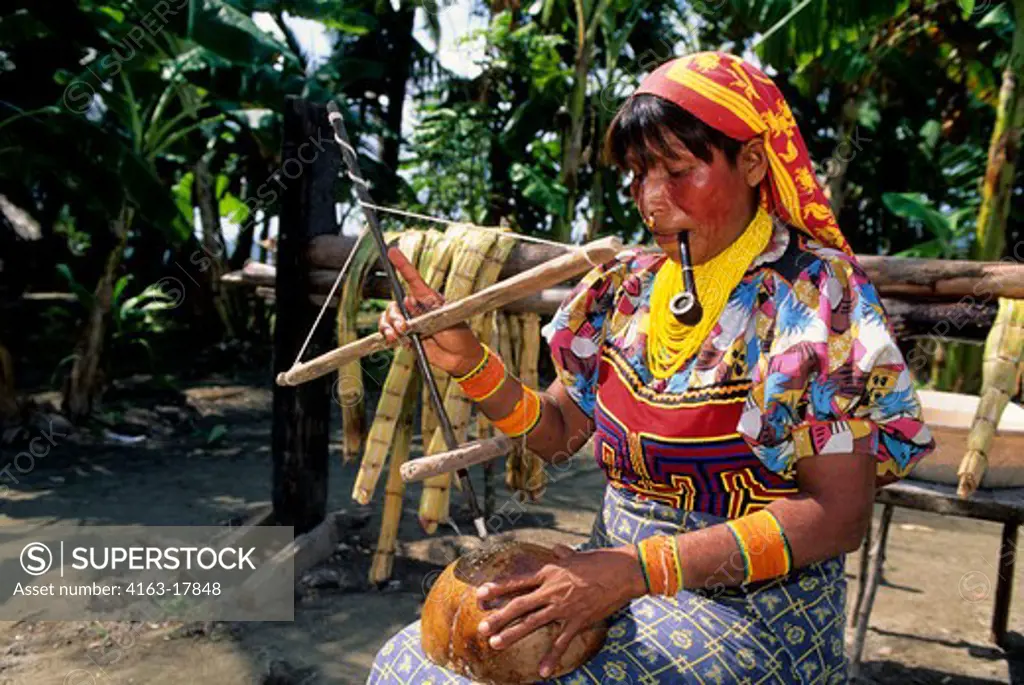 PANAMA, SAN BLAS ISLANDS, ACUATUPU ISLAND, KUNA INDIAN WOMAN USING PRIMITIVE DRILL