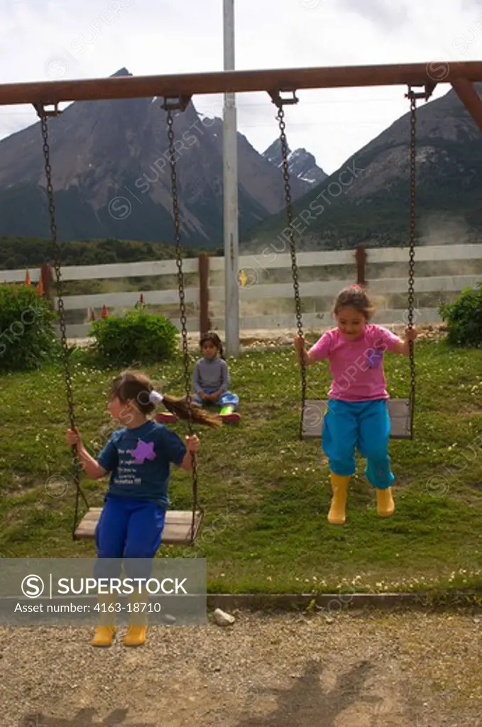ARGENTINA, TIERRA DEL FUEGO, USHUAIA, GIRLS PLAYING ON SWING