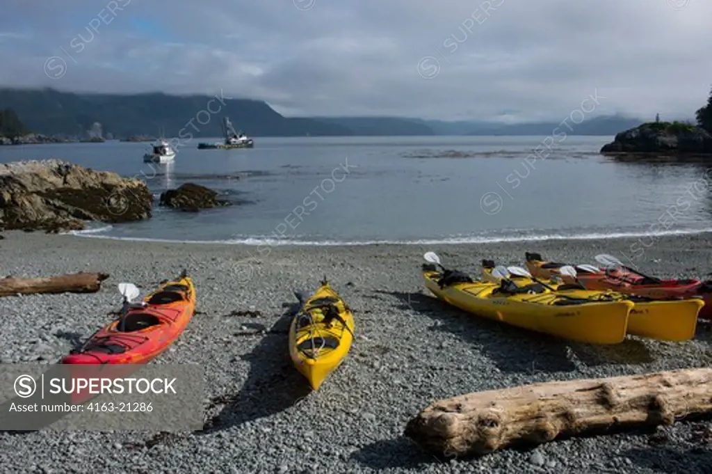 Fishing boats and sea kayaks on beach in bay at George Island, off Chichagof Island, Tongass National Forest, Alaska, USA