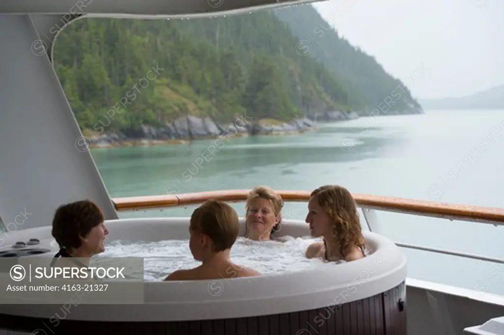 Passengers enjoying the hot tub on the cruise ship Safari Endeavour anchgored at Scenery Cove, Thomas Bay, Tongass National Forest, Alaska, USA