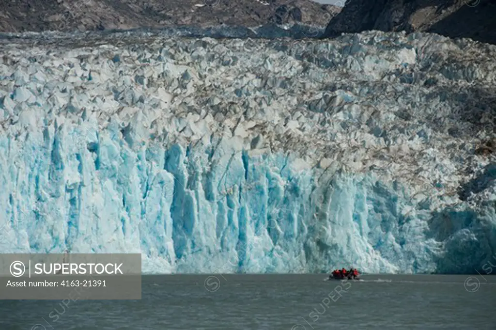 DIP boat with tourists cruising in front of the glacier face of the Dawes Glacier, a tidal glacier, Endicott Arm, Tongass National Forest, Alaska, USA