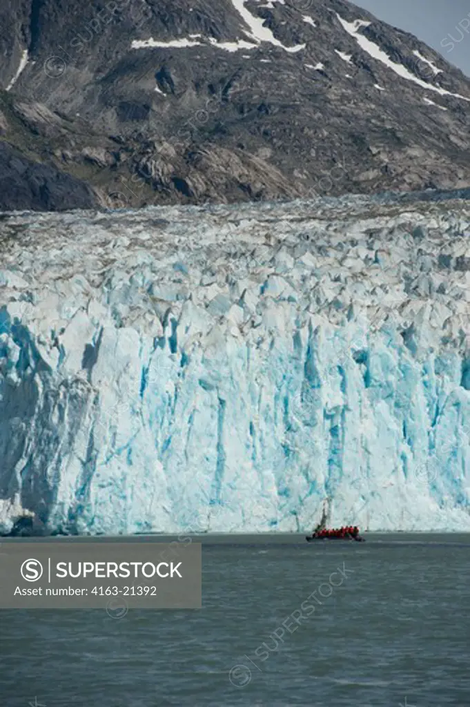 DIP boat with tourists cruising in front of the glacier face of the Dawes Glacier, a tidal glacier, Endicott Arm, Tongass National Forest, Alaska, USA