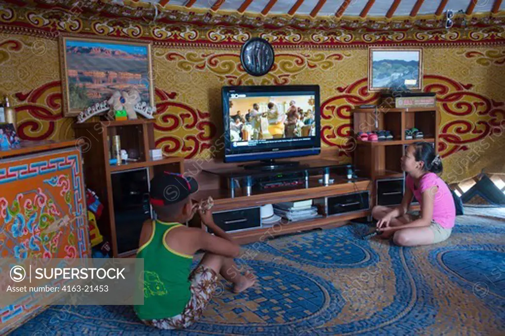 Children Watching Flat Screen Television Inside Ger In The Small Town Of Bulgan In The Gobi Desert, Mongolia