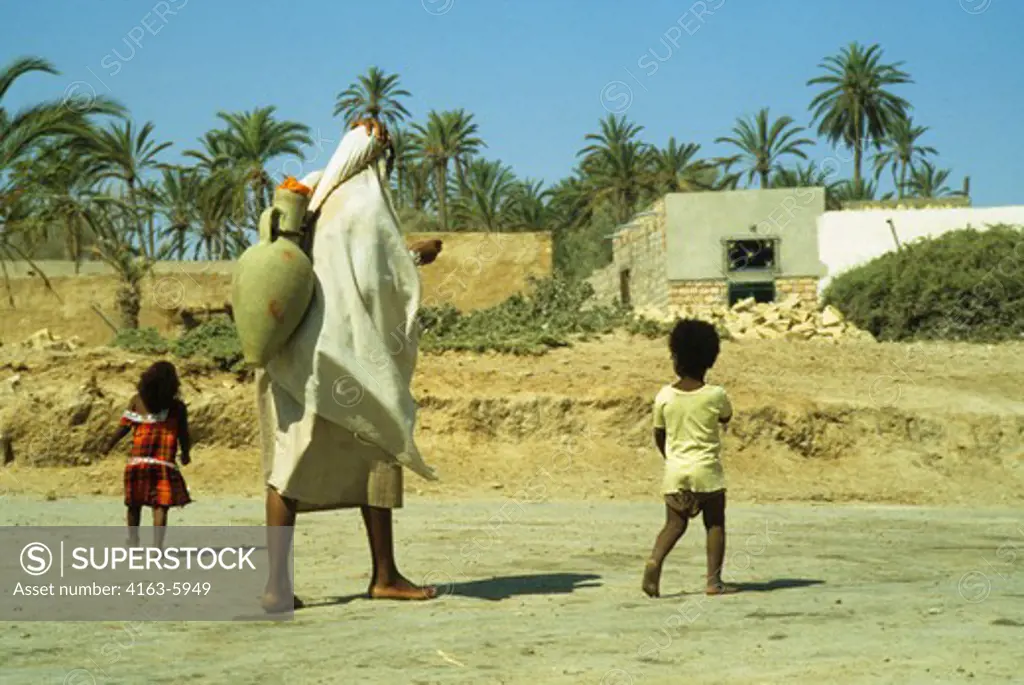 AFRICA, TUNISIA, SAHARA DESERT, OASIS, WOMAN CARRYING WATER FROM WELL