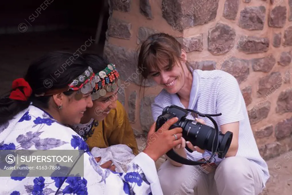 MOROCCO, NEAR MARRAKECH, OURIKA VALLEY, BERBER GIRLS, TOURIST SHOWING PHOTO ON DIGITAL CAMERA