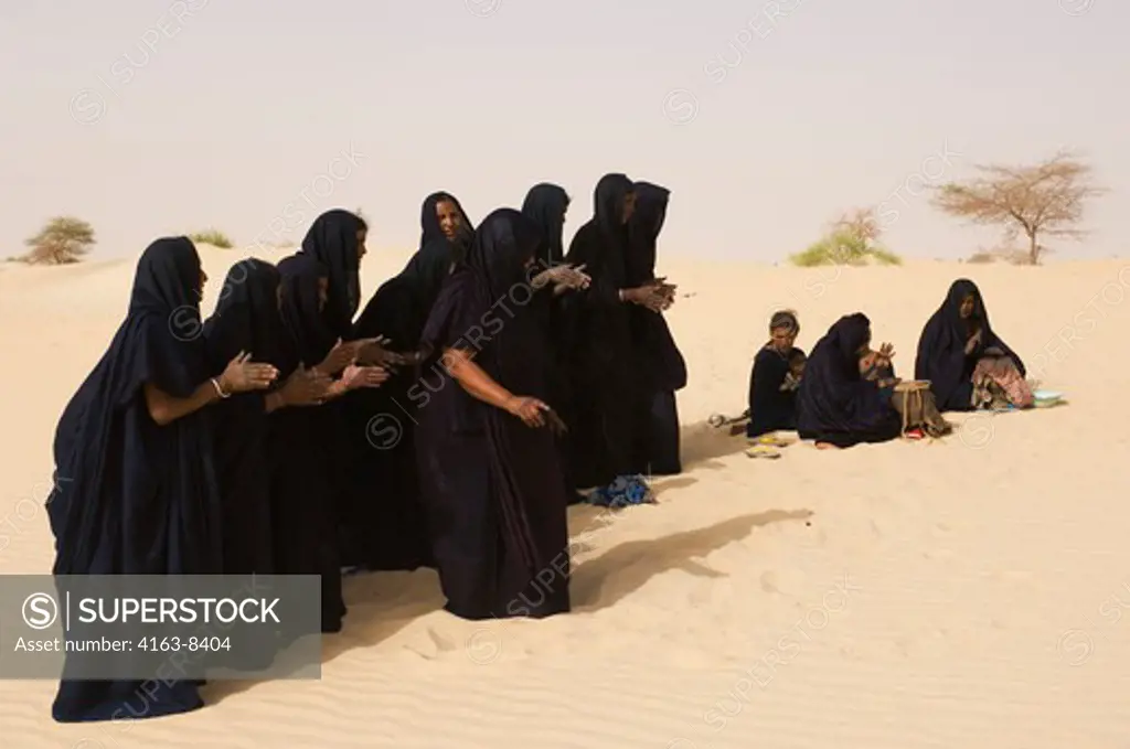 MALI, NEAR TIMBUKTU, SAHARA DESERT, TUAREG WOMEN PERFORMING TRADITIONAL DANCE IN DESERT, CLAPPING WITH HANDS