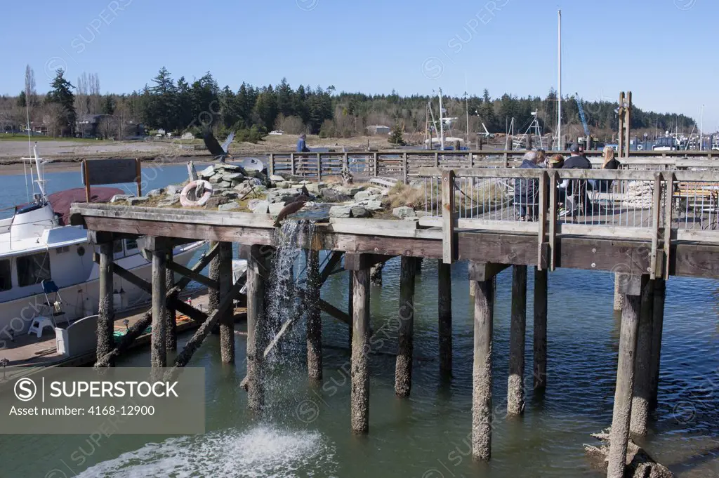 USA,  Washington State, Skagit Valley, La Conner, View Of Canal With Dock, Garden With Waterfall On Dock