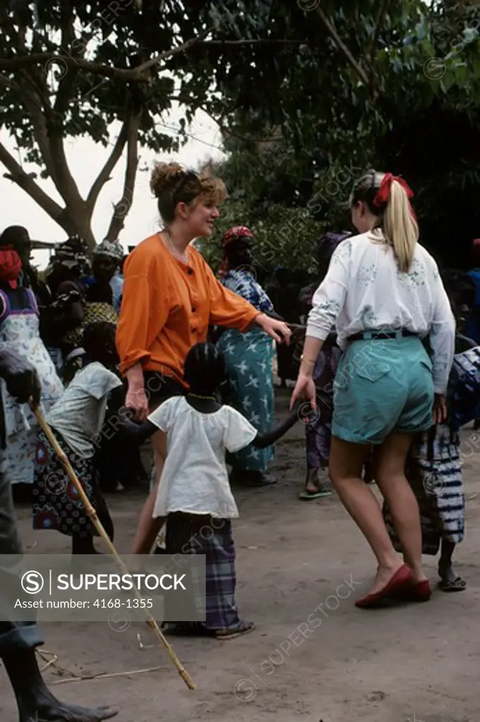 GAMBIA, SMALL VILLAGE NEAR BANJUL, TOURISTS DANCING WITH LOCAL CHILDREN
