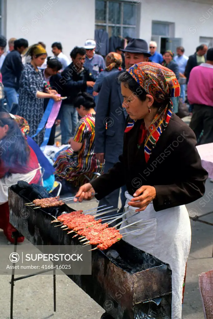A Woman Is Grilling Meat Kebabs On A Charcoal Barbeque At A Market In Urganch, Uzbekistan Along The Silk Road