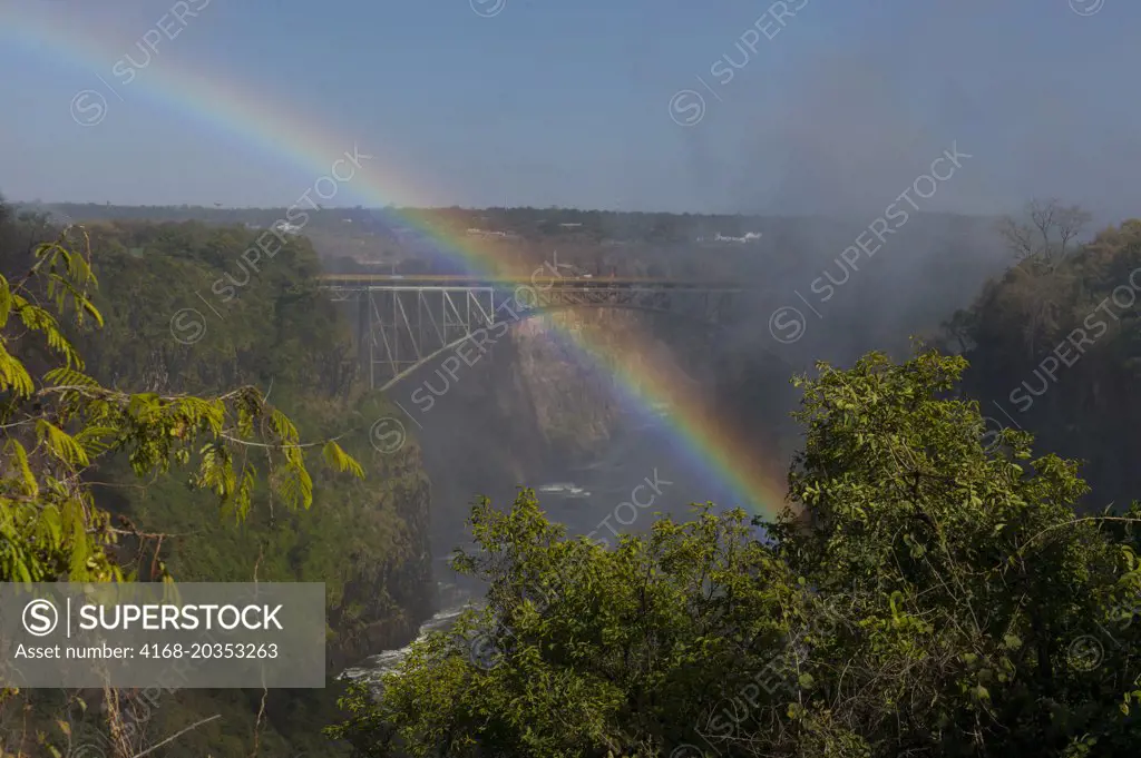 View from Zambia of Victoria Falls Bridge between Zambia and Zimbabwe with rainbow in the spray of the falls.