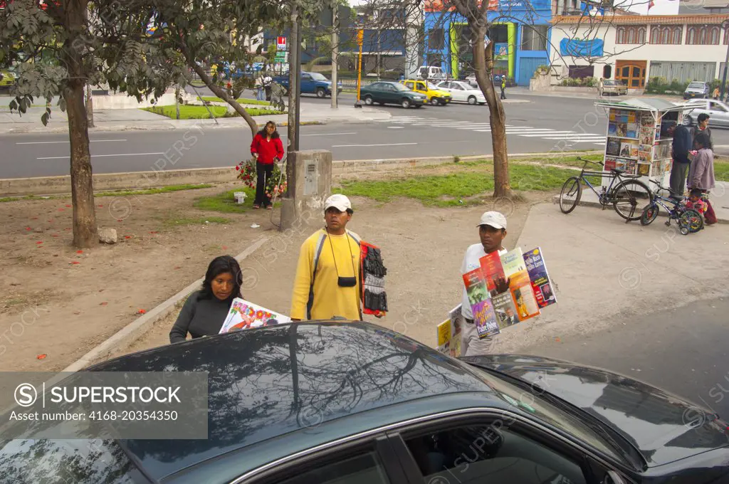 Street vendors selling goods to passing cars on a street in the city of Lima, Peru.
