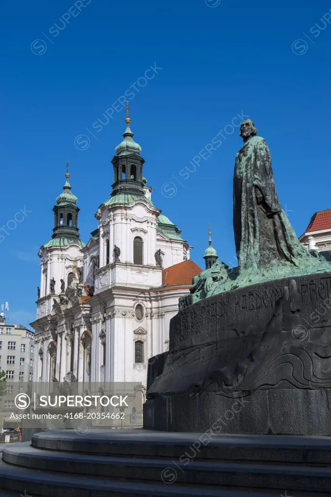 Statue of religious reformer Jan Hus with the baroque St. Nicholas Church at the Old Town Square of Prague, the capital and largest city of the Czech Republic.