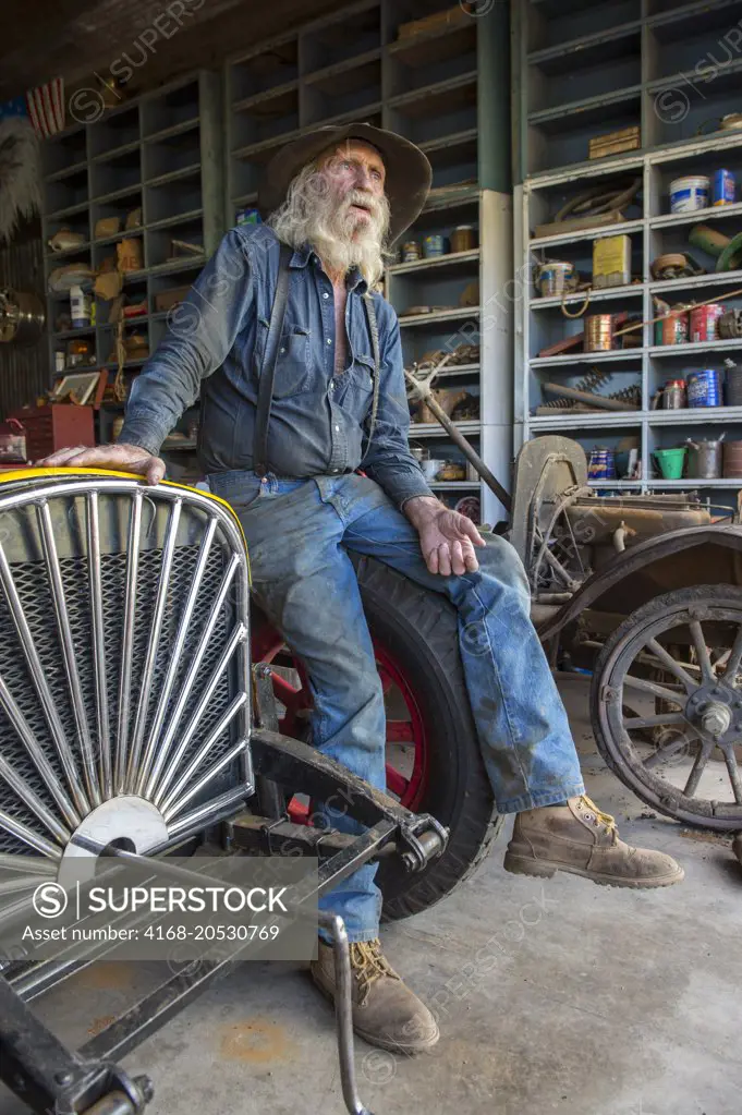 Don Robertson, the owner and founder of the historic Gold King Mine and Ghost Town from the 1890s outside of Jerome in Arizona, USA, in his workshop with his racecar.