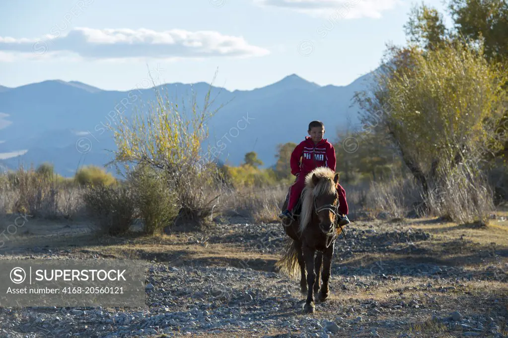 A teenage Kazakh boy is riding a horse near the city of Ulgii (Ölgii) in the Bayan-Ulgii Province in western Mongolia.
