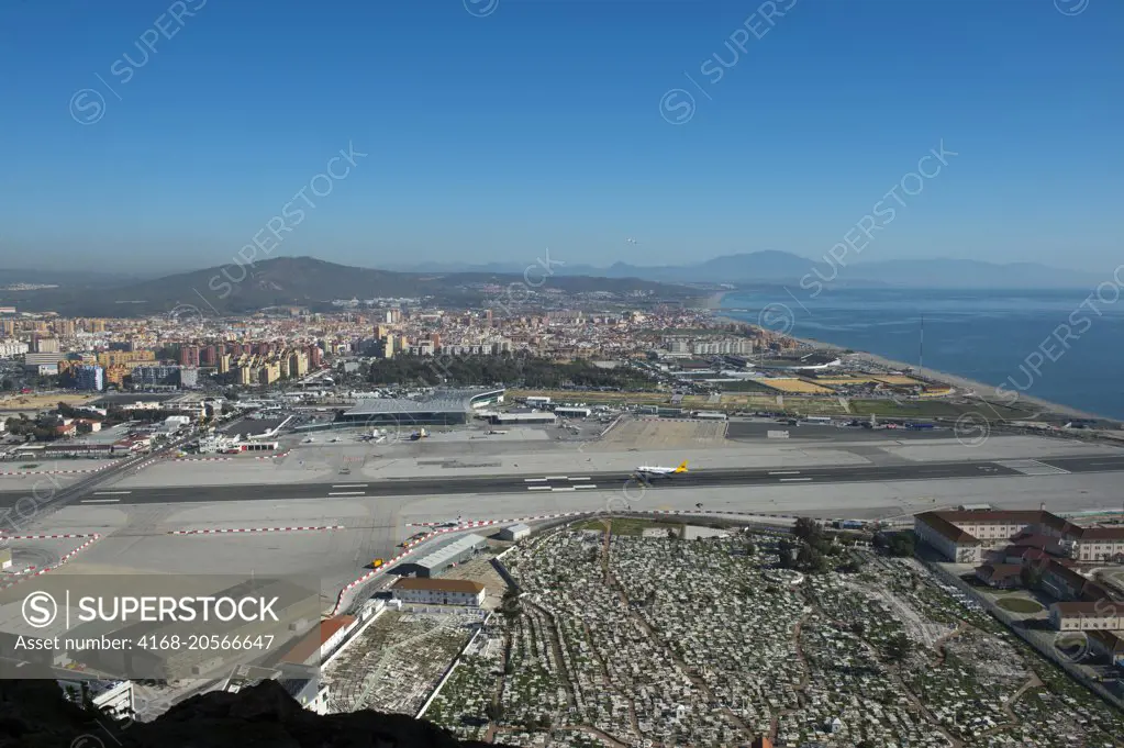 View of the airport with a plane landing and Spain from the World War II tunnels inside of the Rock of Gibraltar, which is a British Overseas Territory, located on the southern end of the Iberian Peninsula at the entrance of the Mediterranean.
