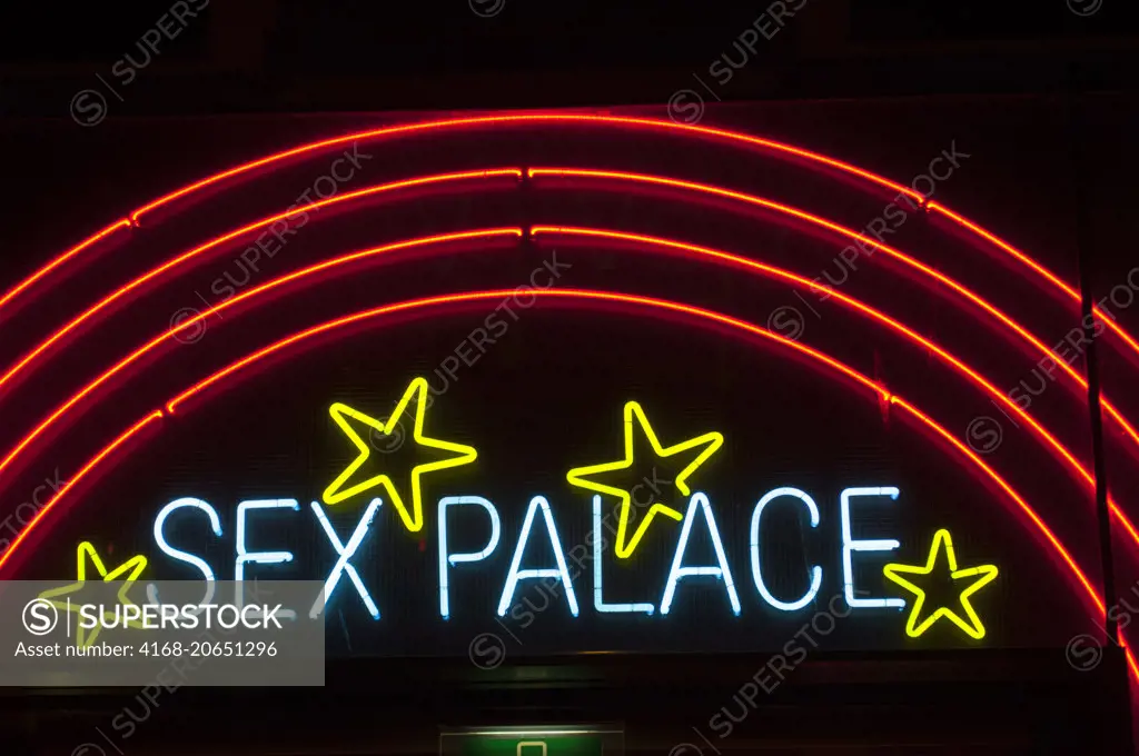 A street scene at night with colorful neon signs of a sex shop in the red light district of Amsterdam in the Netherlands (Holland).