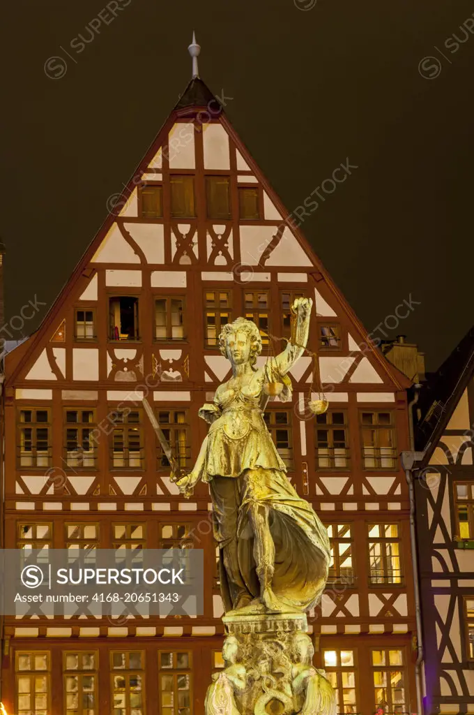 The Fountain of Law and half-timbered houses illuminated at night on the Römer Market Square in the old town of Frankfurt, Germany.