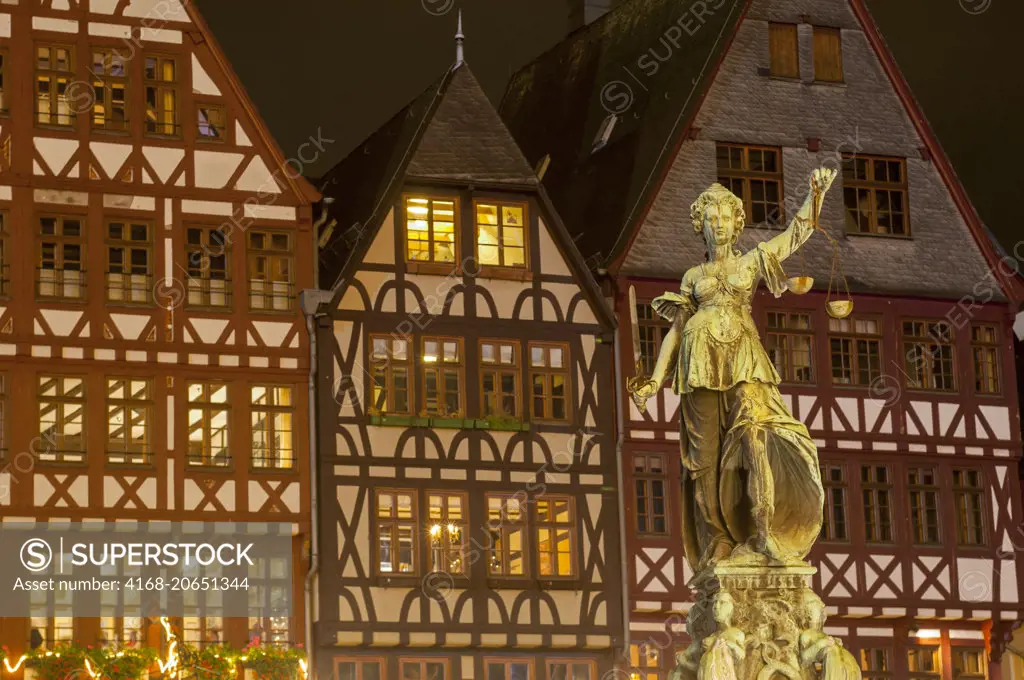 A night photo of the Fountain of Law and half-timbered houses on the Römer Market Square in the old town of Frankfurt, Germany.