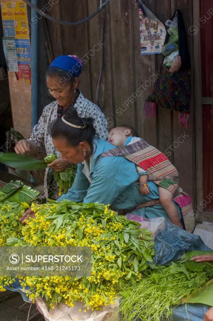 A street scene with women selling Chinese kale at a market in Phou Khoun, Laos.