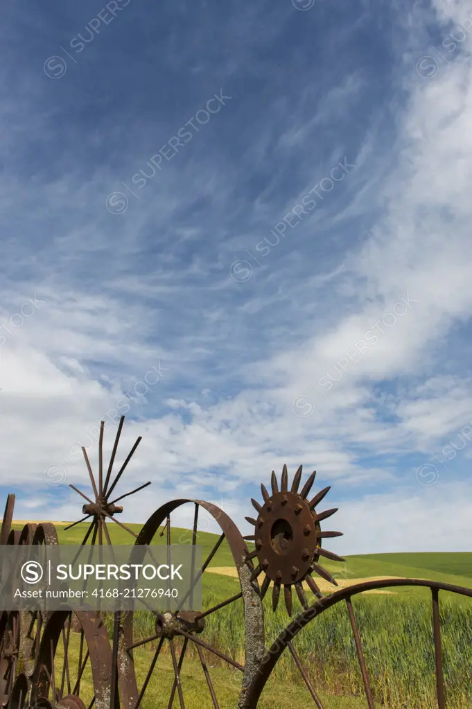 Detail of the metal wheel fence at the Dahmen Barn (Art Barn) in Whitman County in the Palouse near Pullman, Washington State, USA with interesting clouds in the sky.