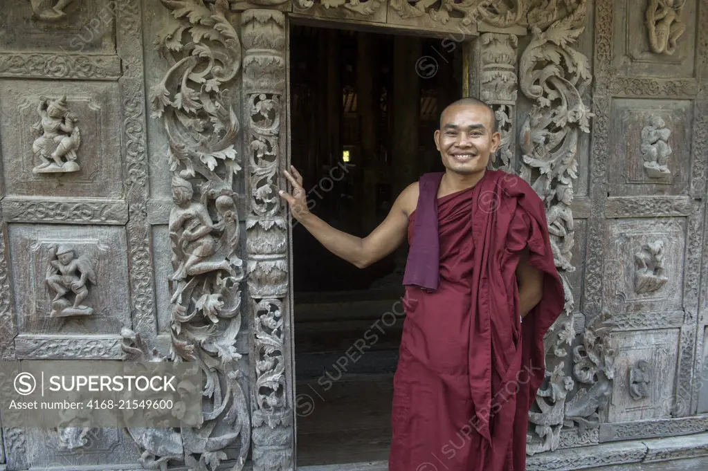 A Buddhist monk is posing at the Shwenandaw Monastery (Golden Palace Monastery), which was built in 1880 by King Thibaw Min and with its teak carvings of Buddhist myths was originally part of the royal palace at Amarapura in Mandalay, Myanmar.