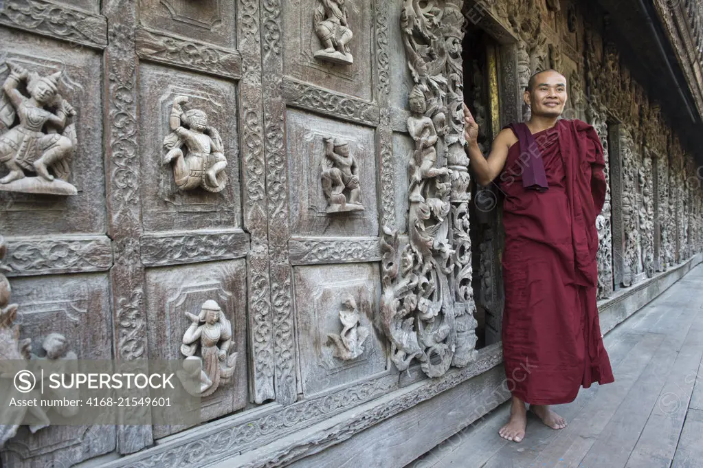 A Buddhist monk is posing at the Shwenandaw Monastery (Golden Palace Monastery), which was built in 1880 by King Thibaw Min and with its teak carvings of Buddhist myths was originally part of the royal palace at Amarapura in Mandalay, Myanmar.