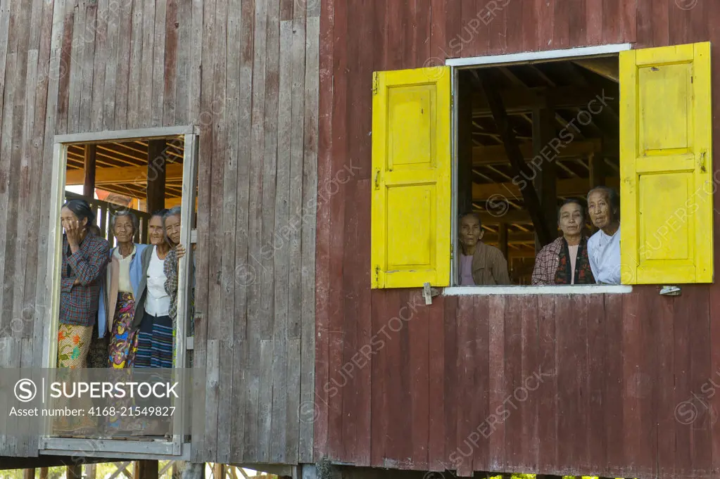 Women looking out of a house at the village of Kuwoo on Inle Lake in Myanmar.