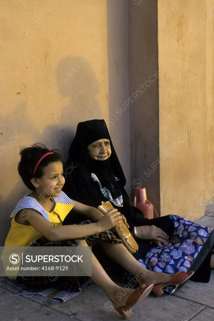 Morocco, Marrakech, Koutoubia Mosque Square, Moroccan Grandmother And Girl, Sitting