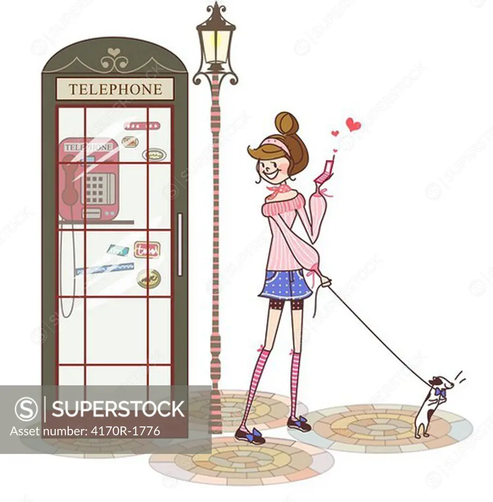Woman standing near a telephone booth and holding a mobile phone
