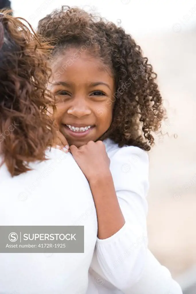Close-up of cute African-American girl in mother's arms