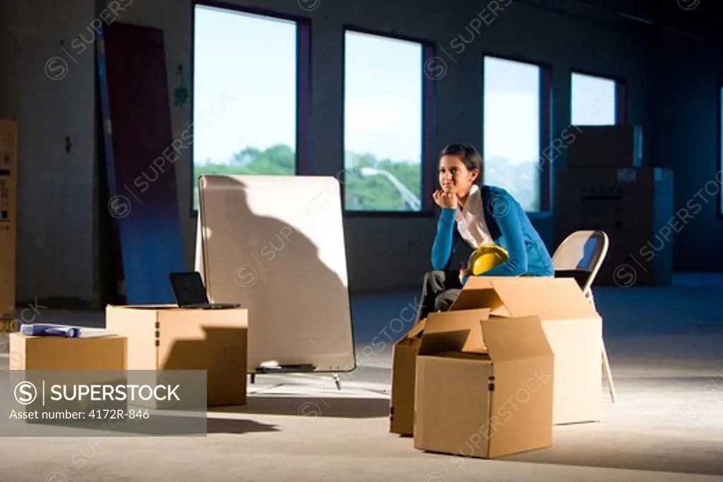 Young woman in empty office space with moving boxes