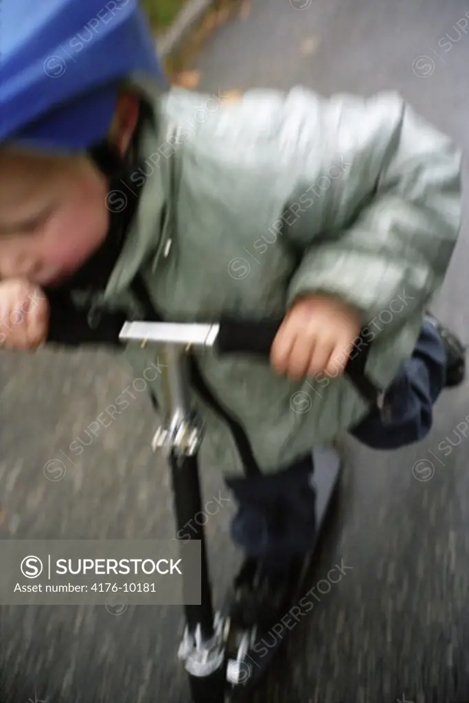 A boy riding a scooter. Sweden